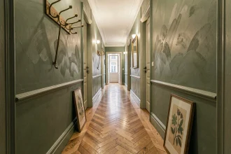 Couloir étroit dans un appartement haussmannien avec peinture vert sauge mate et parquet en point de Hongrie